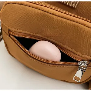 Close-up of caramel nylon bag front zipper pocket showing storage capacity for small items