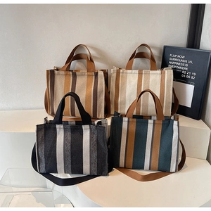 Close-up of four minimalist striped canvas tote bags in different earth-tone colors