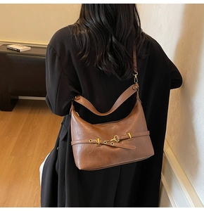 Borsa a mezzaluna in pelle marrone con fibbia metallica indossata da una modella