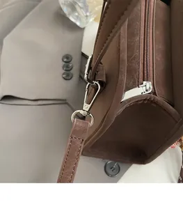 Detail of durable silver metal hook on dark brown suede minimalist shoulder bag