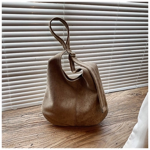 Texture détaillée du sac fourre-tout en daim marron avec bandoulière réglable sur bois