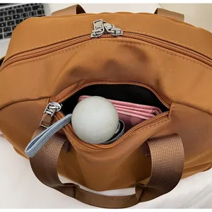 Detail of caramel nylon bag front zipper pocket showing spacious internal storage capacity