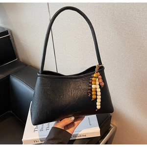 Detail of black faux leather shoulder bag with vintage wooden bead tassel decoration