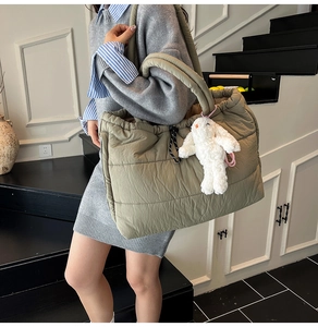 Detailed shot of an olive green quilted puffer tote bag with a plush bunny charm pendant