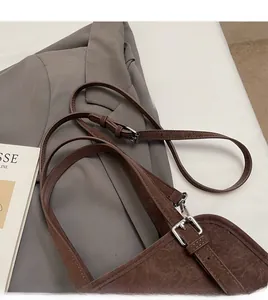 Close-up of brown faux leather shoulder bag with adjustable strap and silver metal buckle