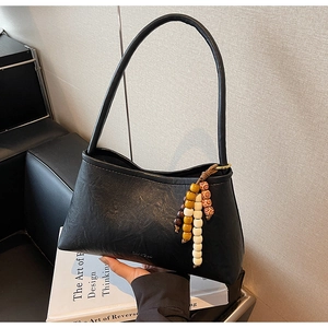Detail of black faux leather underarm bag with unique colorful beaded charm accessory