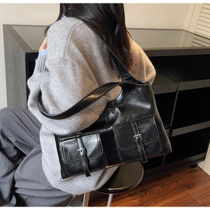 Detail view of a black glossy leather tote bag with silver buckles in a retro chic style