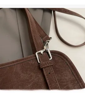 Detail of silver adjustable buckle and dark brown vintage leather strap on a shoulder bag
