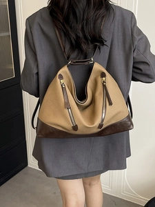 Fashionable khaki canvas and brown leather bucket bag with dual zippers worn by a model