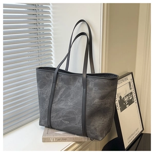 Detailed close-up of dark grey tote bag with marble texture and black leather shoulder strap