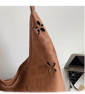 Détail d'un sac cabas marron en daim avec des motifs floraux découpés au laser
