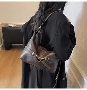 Dettaglio della borsa a tracolla vintage marrone scuro in pelle con fibbia e catena in metallo