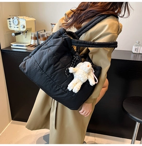 Detail shot of black quilted tote bag with soft puffer texture and cute bunny charm