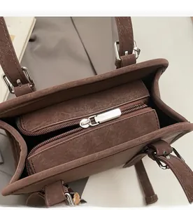 Detail view of smooth silver zipper closure and interior compartment of brown leather bag