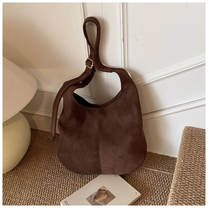 Détail du sac hobo en daim marron avec bandoulière réglable et boucle carrée dorée