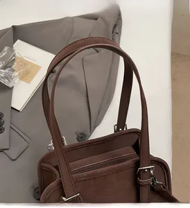 Close-up of matte dark brown minimalist shoulder bag with zipper and metal buckle detail