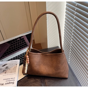 Detail of dark brown matte leather handbag with vintage beaded charm and gold logo