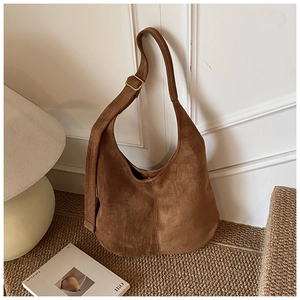 Gros plan du sac en daim marron avec boucle dorée sur un tapis tissé chic