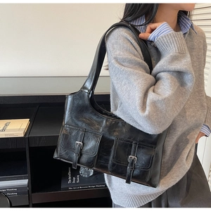 Detail view of black vintage shoulder bag featuring dual front pockets and silver buckles