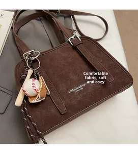 Detail of vintage brown textured leather handbag with unique baseball bat charm accessory