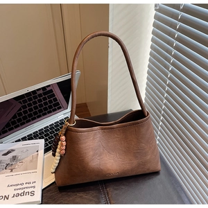 Detail of a brown vintage baguette bag with ethnic beads next to a laptop