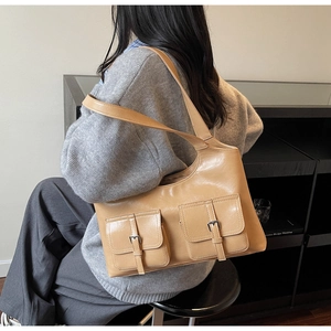 Detail of vintage camel tote bag with double front flap pockets worn over the shoulder