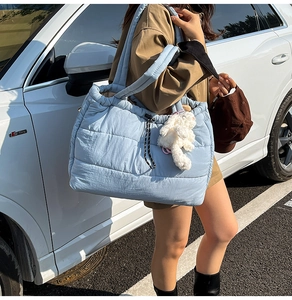 Close-up of light blue quilted tote bag with drawstring and white plush bunny charm