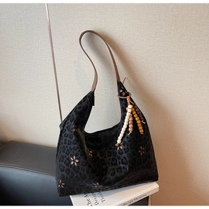 Détail du sac hobo léopard avec motifs floraux découpés au laser et pompons en perles