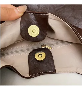 Close-up of golden magnetic snap and zipper closure on vintage brown tote bag