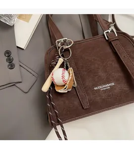 Detail of trendy handbag featuring a mini baseball, bat, and glove bag charm accessories