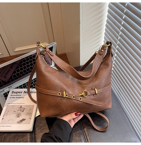 Dettaglio borsa hobo vintage in pelle marrone con fibbia in metallo e tracolla
