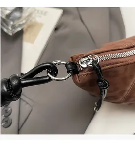 Close-up of premium brown crossbody bag showing polished silver hardware and black leather knot