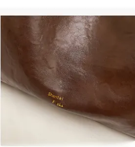 Detailed close-up of dark brown glossy leather texture with golden brand lettering