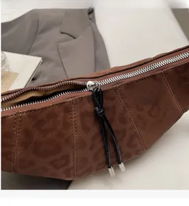 Detail of smooth silver zipper and long knotted pull on leopard print crescent bag