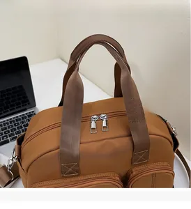 Detail of caramel brown nylon tote bag with dual handles and front zipper pockets