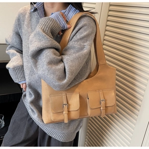 Detail of camel leather shoulder bag with two front pockets and metallic buckles