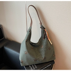 Détail du sac cabas vert ajouré avec motifs floraux et décoration en perles