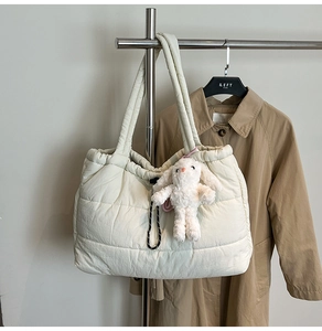 Detail of off-white quilted tote bag with drawstring closure and cute bunny charm