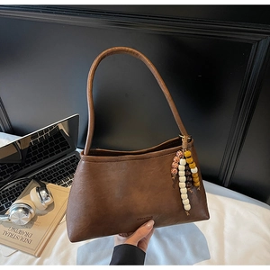 Detail of retro brown leather shoulder bag with colorful beaded charm and zipper