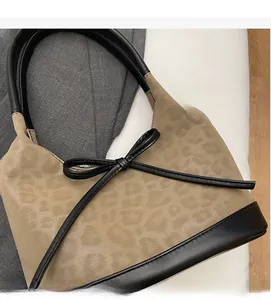 Detail of leopard print suede bucket bag with black leather bow and handle