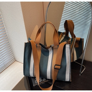 Close-up of striped canvas tote bag with adjustable strap on a wooden table setup