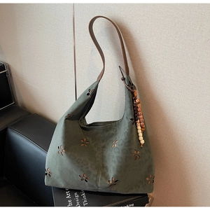 Détail du sac cabas vert foncé avec découpes laser florales et pompon en perles vintage