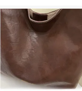 Macro shot of dark brown tote bag with stitching detail and textured faux leather surface
