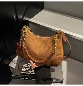 Detail view of brown suede hobo bag with gold chain strap and red cherry charm