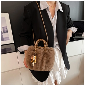 Detail der braunen Plüschtasche mit geflochtenem Griff und Perlenanhänger-Accessoire