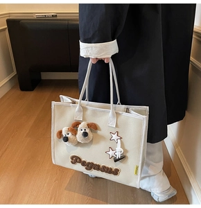 Détail du sac fourre-tout en toile beige avec tête de chien en peluche et broderie Pegasus