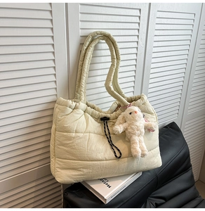 Close-up of quilted beige tote bag with soft plush bunny keychain and drawstring detail