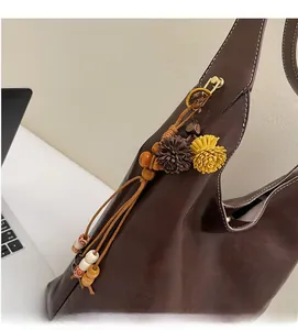 Detail of dark brown leather hobo bag with wooden beads tassel and golden buckle