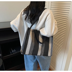 Detail of knitted striped tote bag showing woven texture and dual handle design on a model