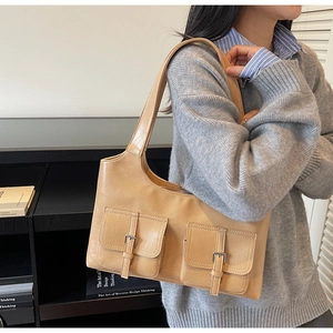 Detail of light brown leather underarm bag with double buckle pockets on a grey sweater